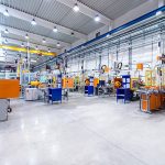 Horizontal image of huge new modern factory with robots and machines producing industrial plastic pieces and equipment. Wide angle view of futuristic machines standing on flooring and having the monopole of all work, taking the place of human work. There is not necessary use human hand. Wide angle, view, no people, space for copy.